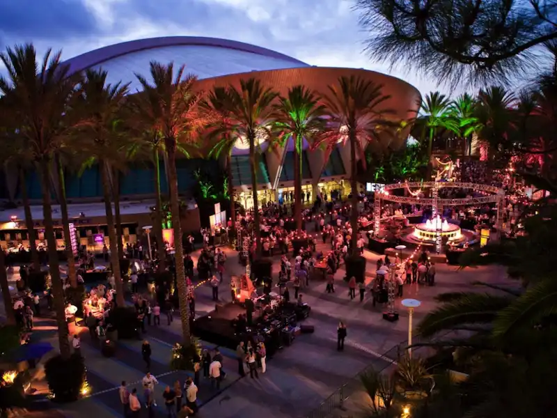 Evening crowds at an outdoor event plaza beside the Anaheim Convention Center arena